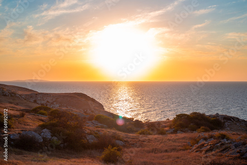 Sunset Seascape. Rocky seashore with yellow sun-scorched grass and a beautiful sky. Travel and tourism.