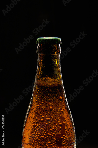 Close-up of brown beer bottle with green cap against black background. Bubbles lager foamy beer. Concept of alcohol and non-alcohol drinks, refreshment. Poster, banner for ad