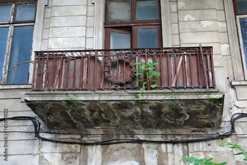 An abandoned house with a dilapidated balcony and rusted railing