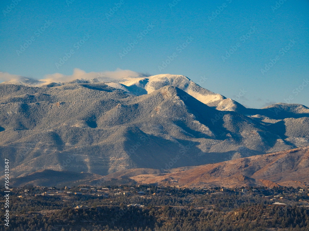 Vapor Clouds Trailing off the Peaks of a Snow Capped Rocky Mountain Under a Clear Blue Sky in Colorado