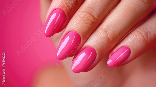 A woman s hand with a neat manicure and bright pink nail polish.