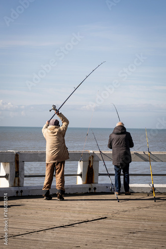 a fisherman casts his fishing rod on the pier while sea fishing