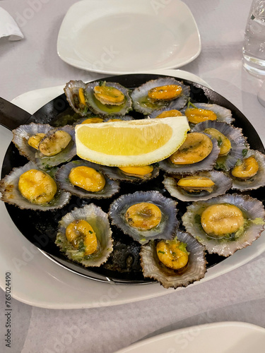 Cooked Lapas limpets mussels with garlic, herbs and lemon on a plate close up photo