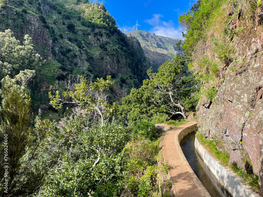 Obraz premium Stunning view of the beautiful hiking trail Levada do Moinho on a sunny day on Madeira island, Portugal
