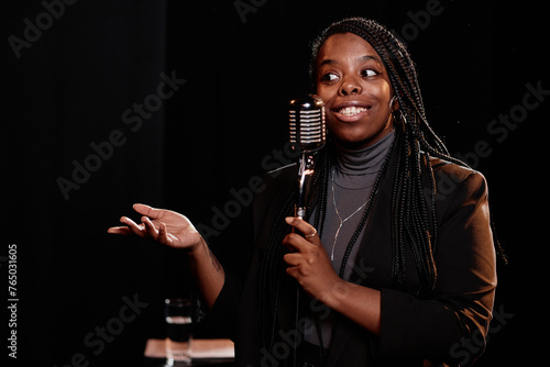 Fotografie Waist up portrait of young Black woman speaking to microphone performing in stan