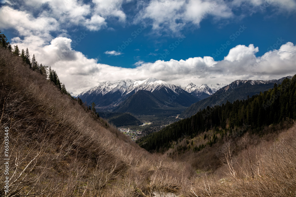 Beautiful mountain landscape. Clouds in the sky. Green grass. Snow on mountain peaks.	