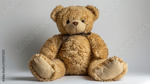 A seated classic teddy bear with a bowtie, featuring a warm expression and plush texture, on a subtle grey backdrop.