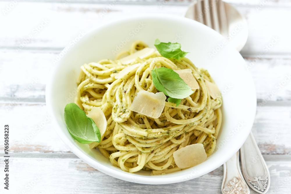 Spaghetti with olive pesto sauce and fresh basil. Bright wooden background. Close up