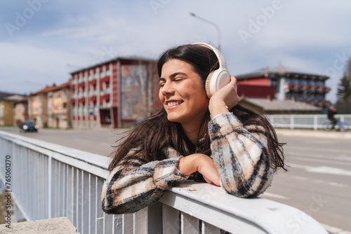 One young girl is listening to music on her wireless headphones and enjoying the sun outdoors  © Dusan