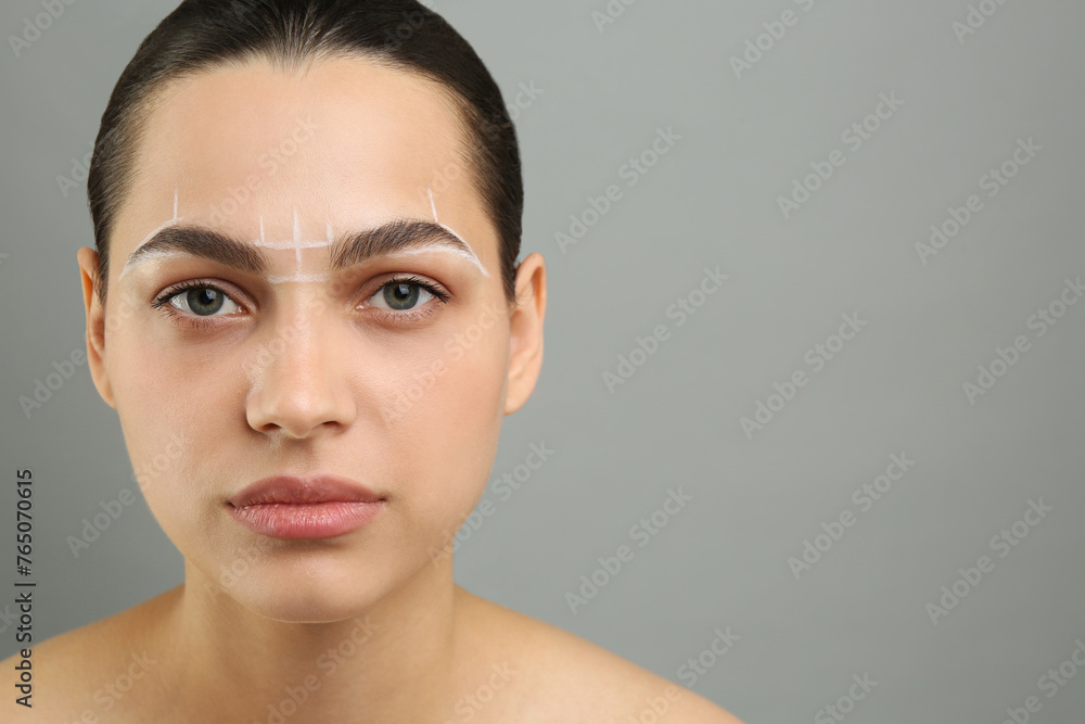 Eyebrow correction. Young woman with markings on face against grey background, space for text Eyebrow correction. Young woman with markings on face against grey background, space for text