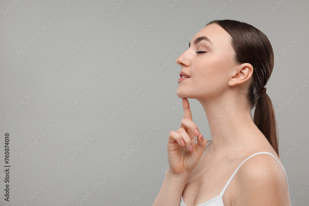 Beautiful woman touching her chin on grey background. Space for text Beautiful woman touching her chin on grey background. Space for text