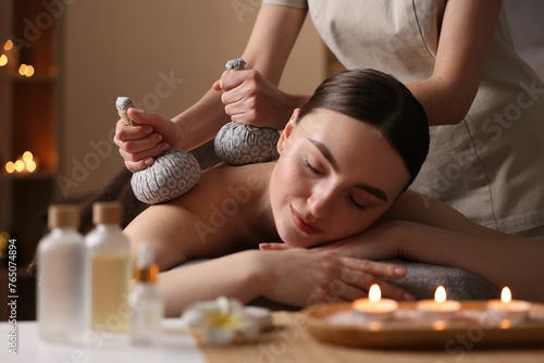 Spa therapy. Beautiful young woman lying on table during herbal bag massage in salon