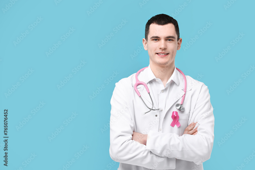Portrait of smiling mammologist with pink ribbon and stethoscope on light blue background. Space for text Portrait of smiling mammologist with pink ribbon and stethoscope on light blue background. Space for text