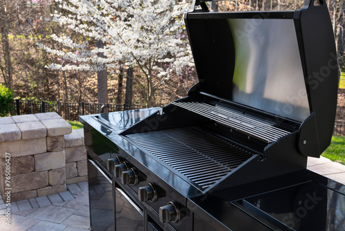 Backyard garden view with a black gas grill in springtime. Outdoors cooking concept.