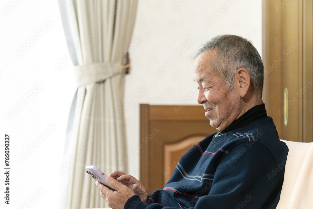 Fototapeta premium 笑顔でスマホを操作する高齢者の男性
