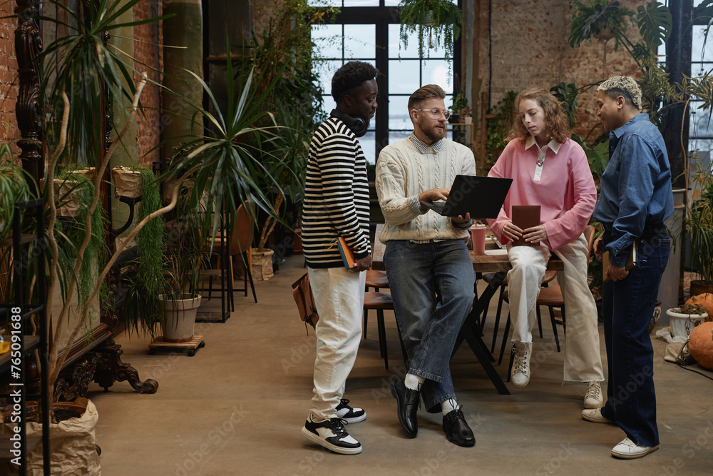 Fototapeta premium Full length portrait of diverse young business team discussing project standing in coworking space copy space