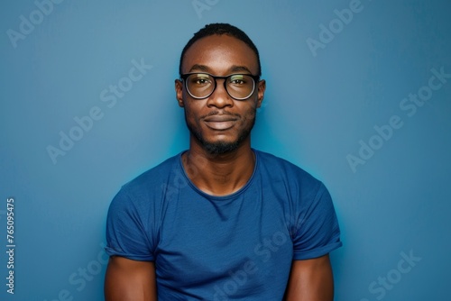 Attractive african american man wearing blue tshirt and glasses. Isolated on blue background.