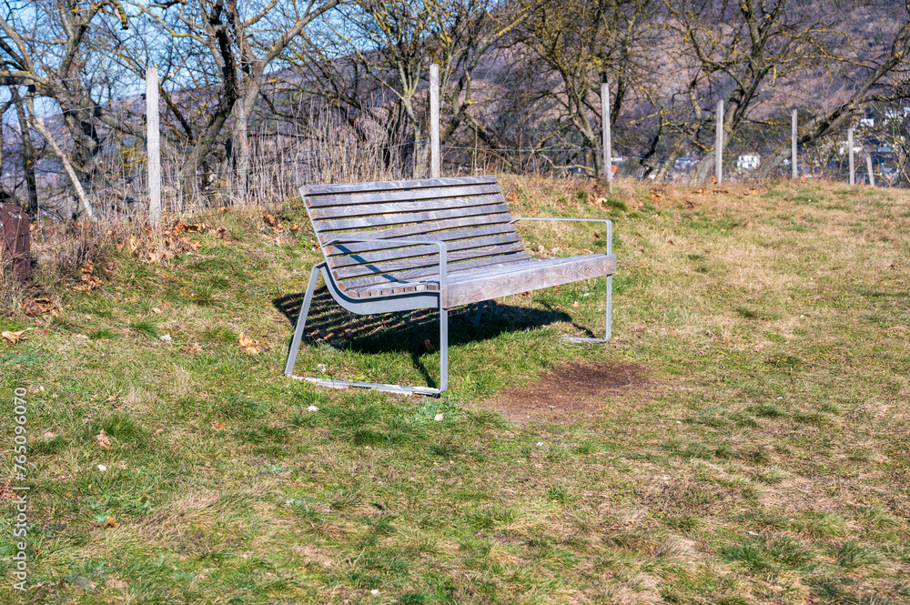 Wooden bench on the meadow. There are trees and hills in the background. Autumn. Wooden bench on the meadow. There are trees and hills in the background. Autumn.