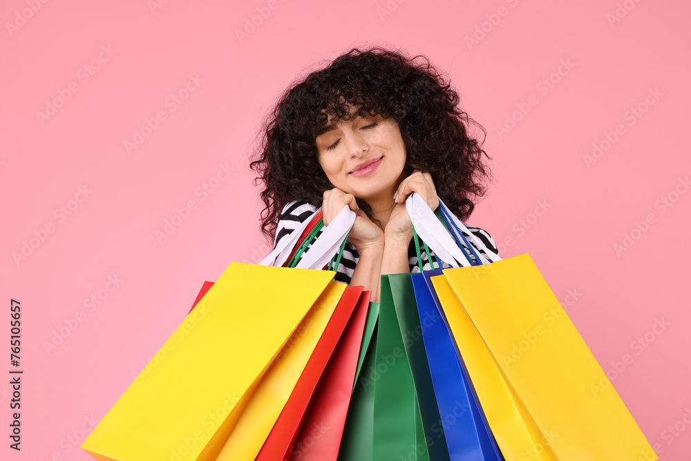Happy young woman with shopping bags on pink background Happy young woman with shopping bags on pink background