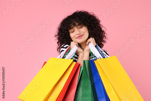 Happy young woman with shopping bags on pink background © New Africa