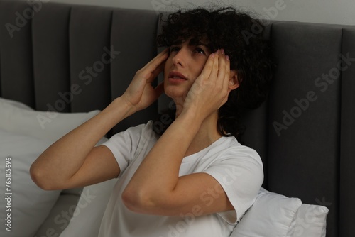 Young woman suffering from headache in bed at night