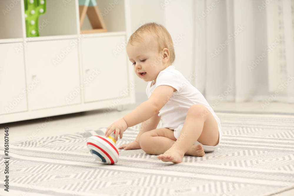 Children toys. Cute little boy playing with spinning top on rug at home Children toys. Cute little boy playing with spinning top on rug at home
