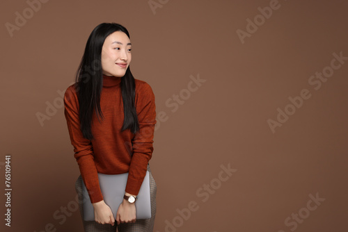 Portrait of beautiful woman with laptop on brown background. Space for text