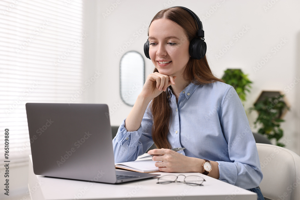 E-learning. Young woman using laptop during online lesson at white table indoors E-learning. Young woman using laptop during online lesson at white table indoors