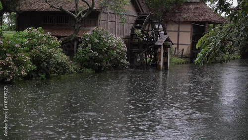 雨が降る中ユックリ流れる川と回る水車と水車小屋、固定撮影、環境音あり