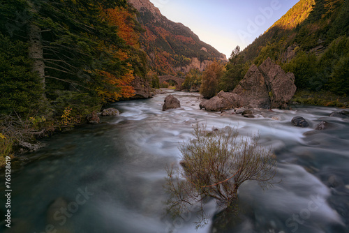 Dawn in the Bujaruelo valley, in the Aragonese Pyrenees, with the sun rising between the mountains and in front of the Romanesque bridge and the Ara river