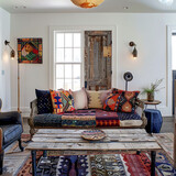 Eclectic family room with a patchwork sofa, mismatched vintage chairs, and a salvaged door repurposed as a coffee table.
