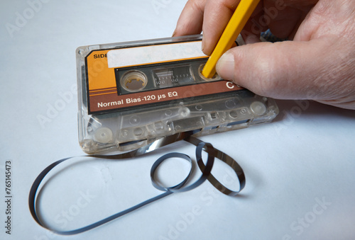 Vintage audio cassette and rewinding the magnetic data carrier with wooden pencil. photo