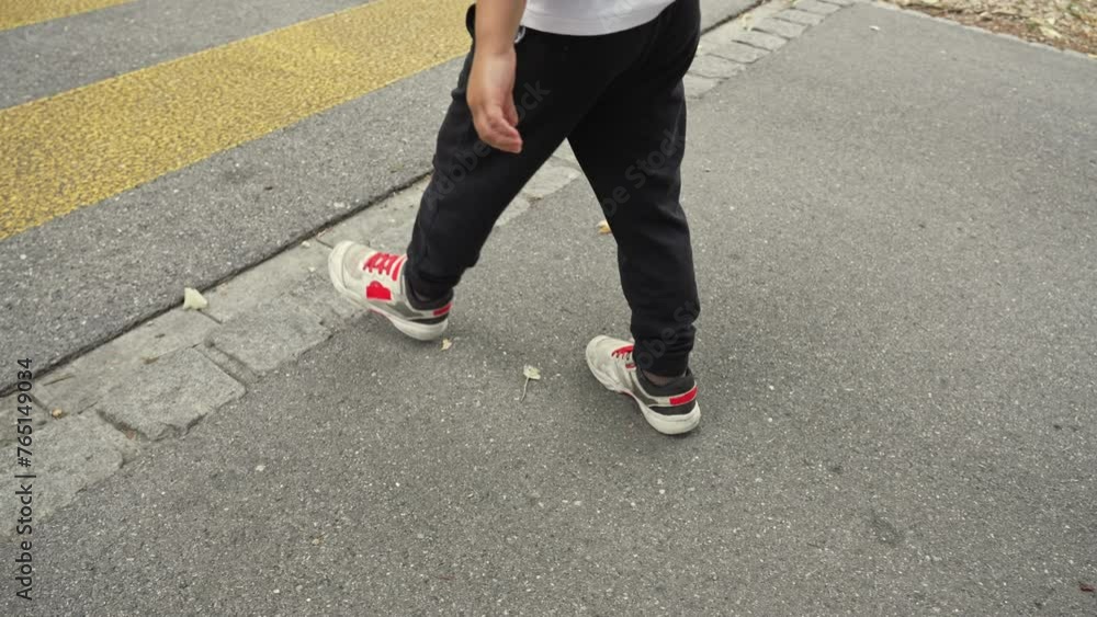 Young Boy Checks Velcro Sneakers While Pausing During Walk Outside In Street Young Boy Checks Velcro Sneakers While Pausing During Walk Outside In Street