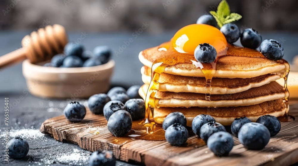 a stack of pancakes on a cutting board with blueberries and syrup being drizzled on top of them. a stack of pancakes on a cutting board with blueberries and syrup being drizzled on top of them.