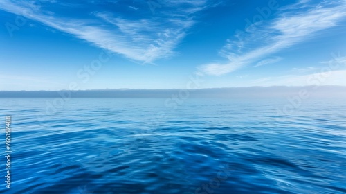 a large body of water with a blue sky and some clouds in the middle of the water and a small island in the middle of the water.