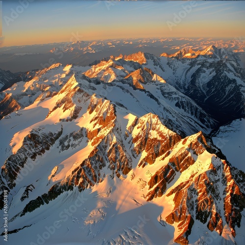an aerial view of a mountain range with snow on the mountains and the sun shining on the top of the mountain.
