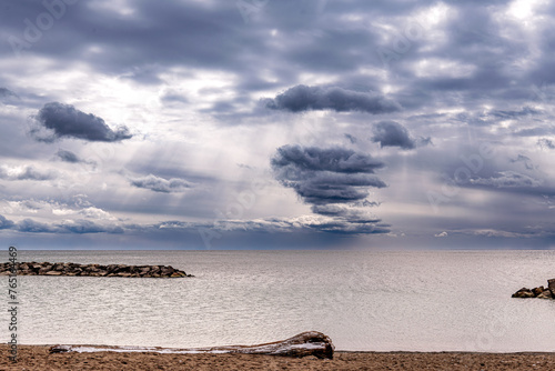 Pillars of lights and dramatic clouds over Lake Ontario with rocks, waves and ice. Suitable for background, space for text.	
 photo