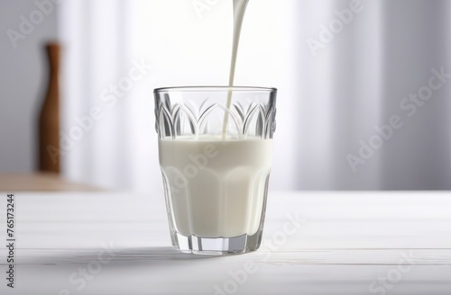 glass into which milk is poured on white wooden table