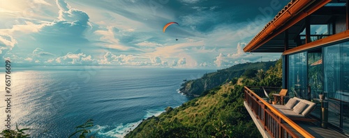 Modern cliffside villa overlooks the ocean with a paraglider soaring by, signifying luxury living and adventure.