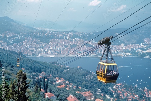 An image depicts a cable car with passengers, set against an expansive view of a city below and the sea in the distance, likely a form of tourism or transport in a hilly or mountainous region