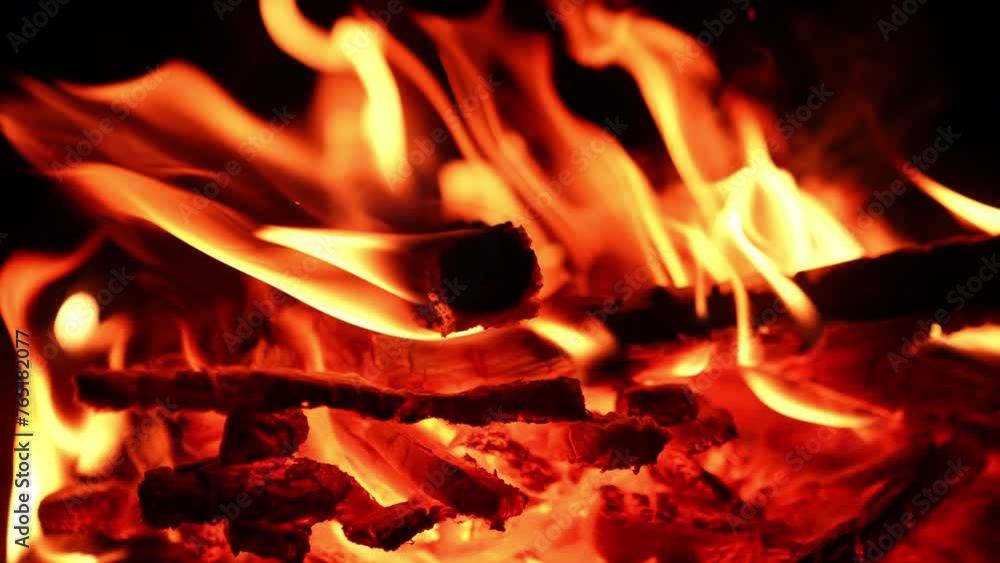 Burnt out logs break in the campfire and fall. Flames of fire are still burning well in the bonfire. Close up. Burnt out logs break in the campfire and fall. Flames of fire are still burning well in the bonfire. Close up.