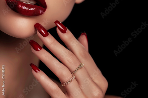 Close-up of hand and lips with red lipstick, showing manicure in elegant style, on dark background