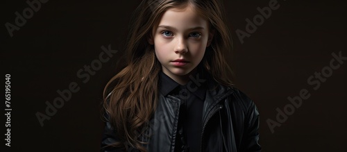 A young girl, with layered hair and fur collar, is wearing a black leather jacket and black shirt. She looks like a fictional character in darkness, ready for portrait photography at an art event