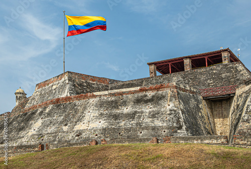 Fotografie Cartagena, Colombia - July 25, 2023: Closeup, gray-beige stone San Felipe de Barajas Fort ramparts and national flag