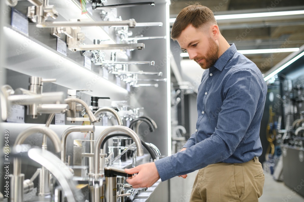 a customer in a hardware store in the plumbing department chooses a faucet for the kitchen a customer in a hardware store in the plumbing department chooses a faucet for the kitchen