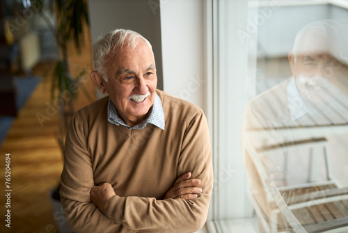 Happy mature man looking through window at home