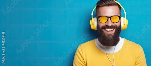 This image features a man sporting a beard while wearing vibrant yellow headphones photo