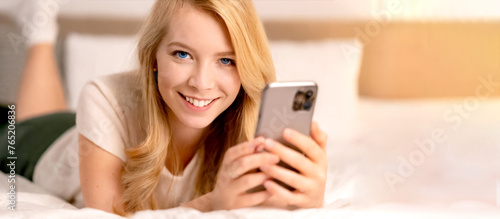 Frau liegt im Bett und surft mit dem Smartphone  photo