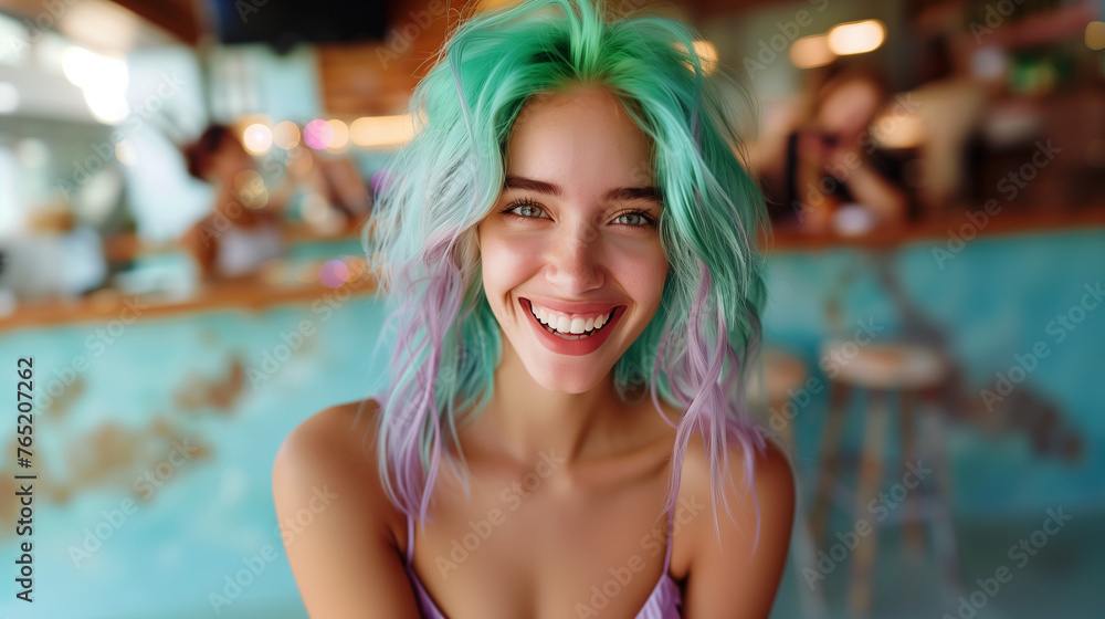 Woman with teal and lilac hair smiling in a cafe setting.