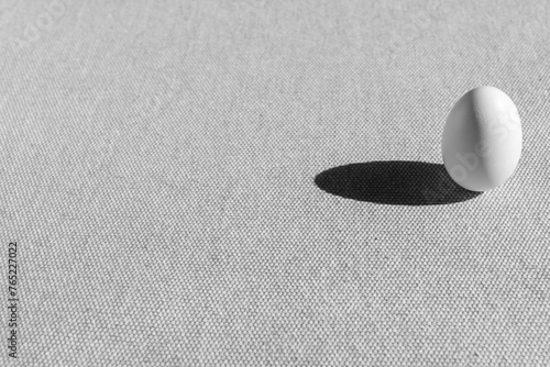 Photography Fresh white small chicken egg on grey background.